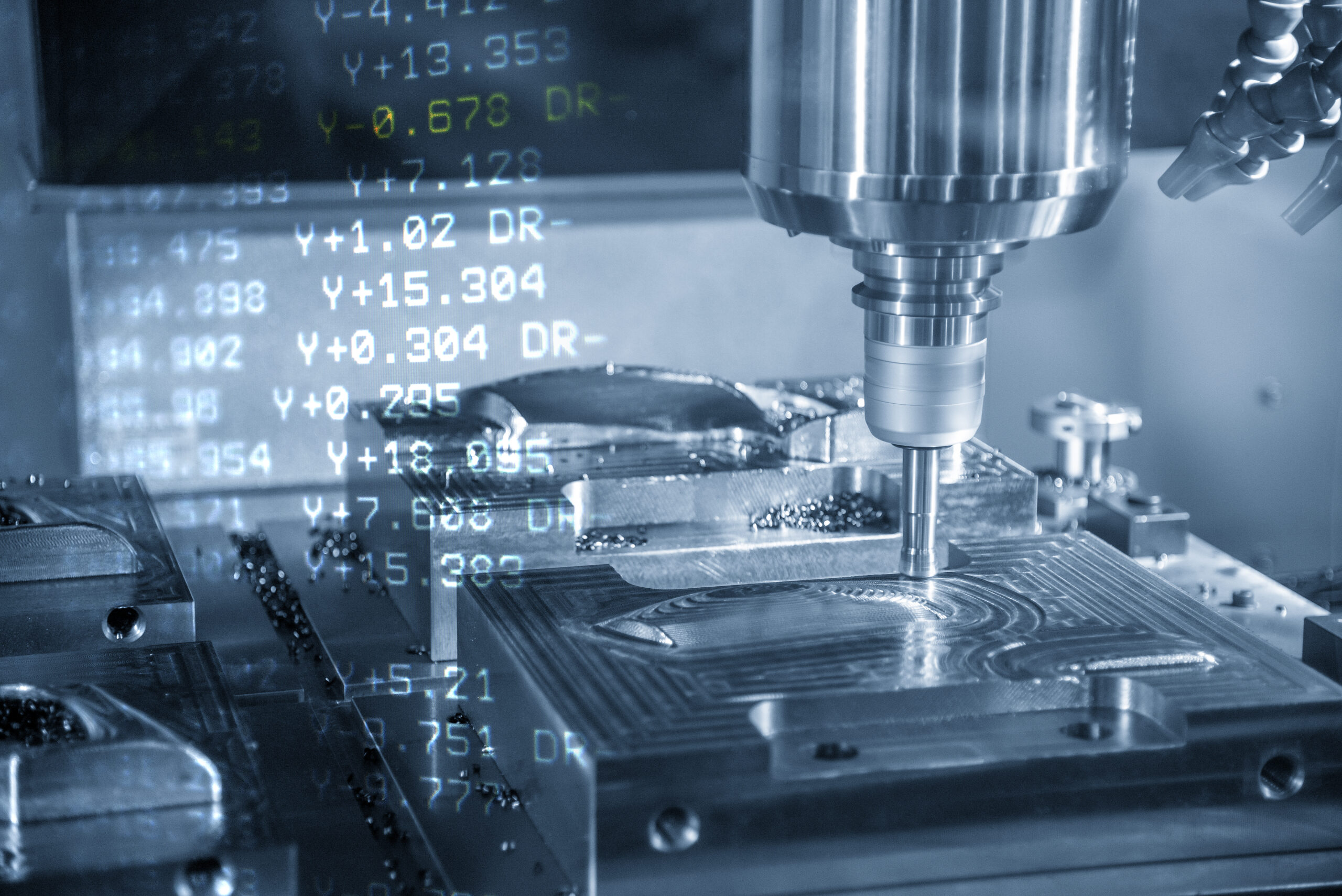 The CNC machining centre with the G-code data background. The CNC milling machine cutting the mould parts.